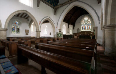 The interior of a church, with brown pews and white arches and pillars