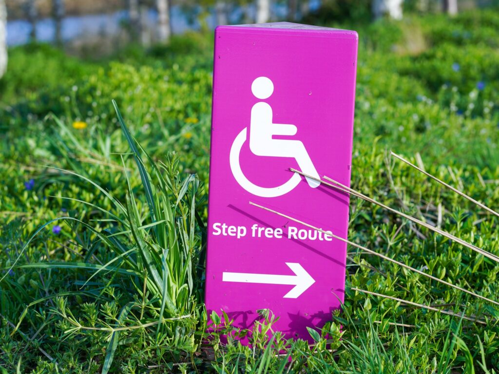 A pink sign on a green lawn reads 'Step-free access' with an arrow pointing to the right